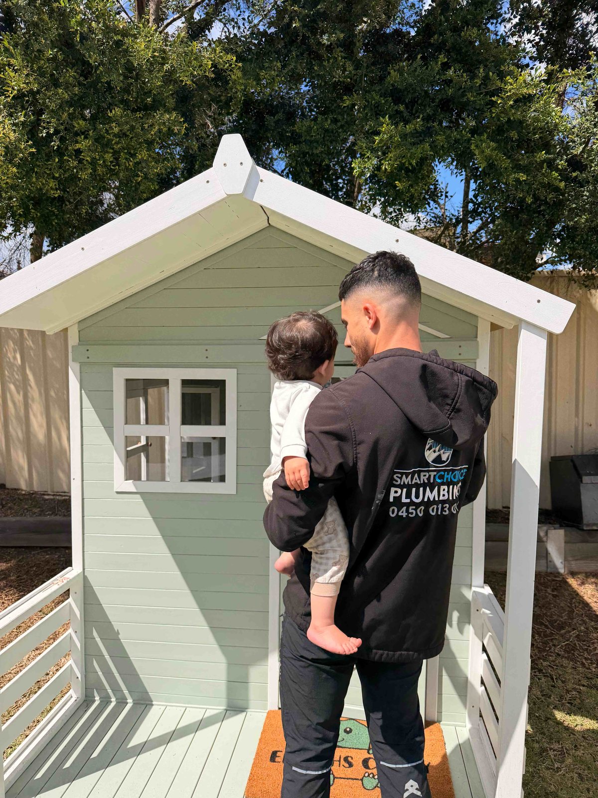Hassan Abdallah of Smart Choice Plumbing holding his son, a family-owned Campbelltown plumbing business
